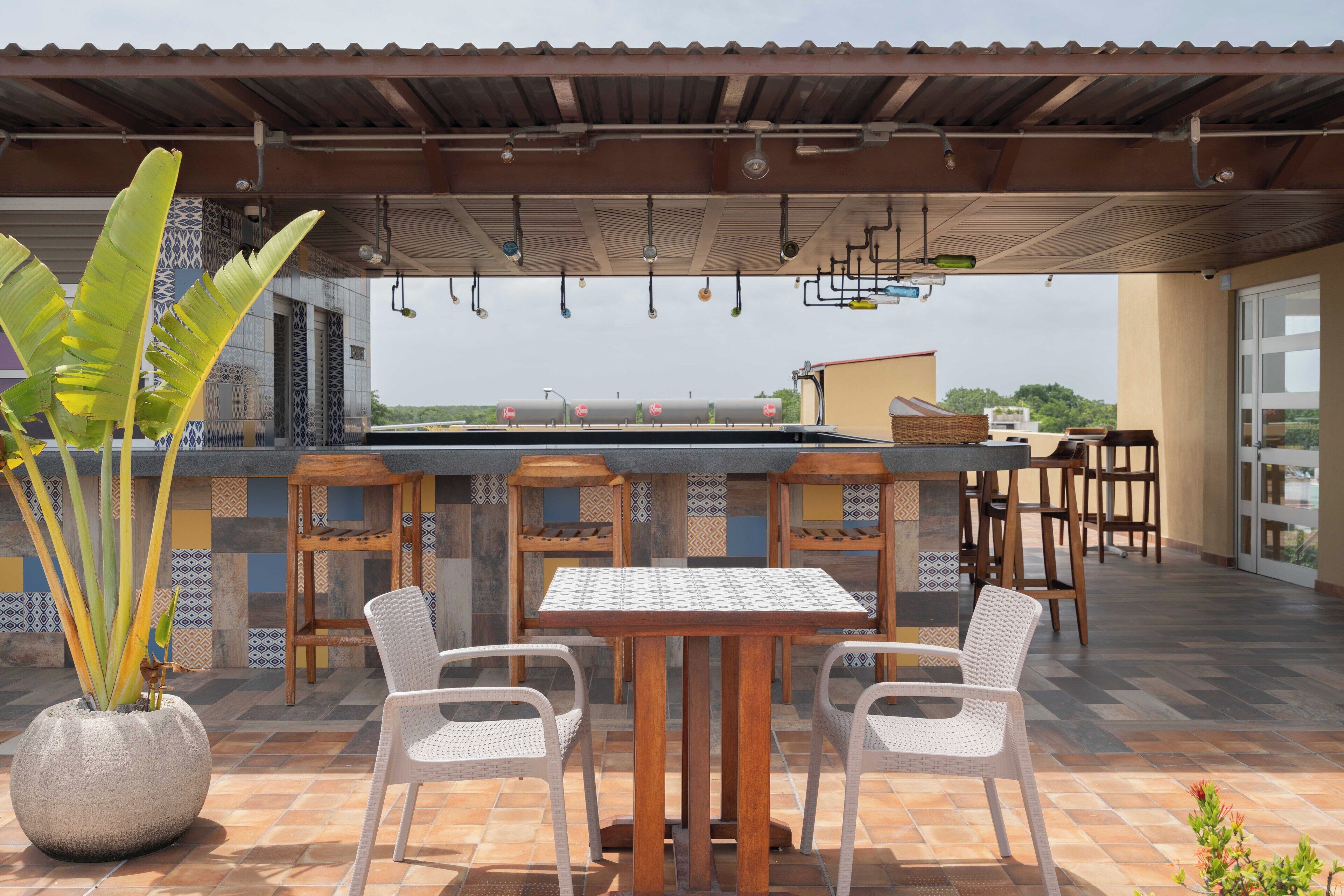 An outdoor patio with a bar, seating, and a large potted plant.