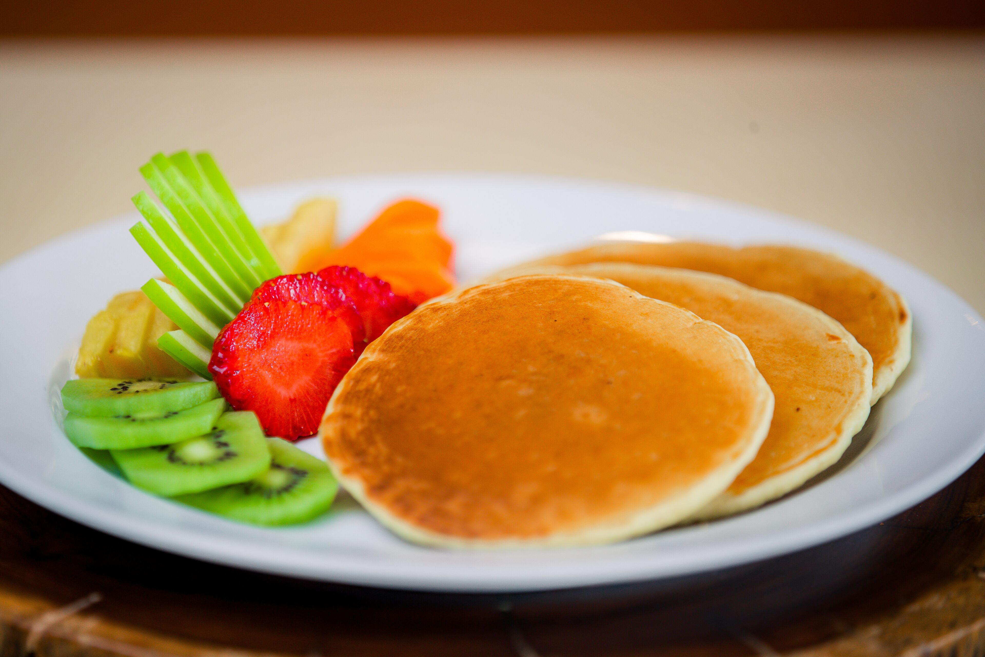 Un plato con tortitas, fresas, kiwi y apio.