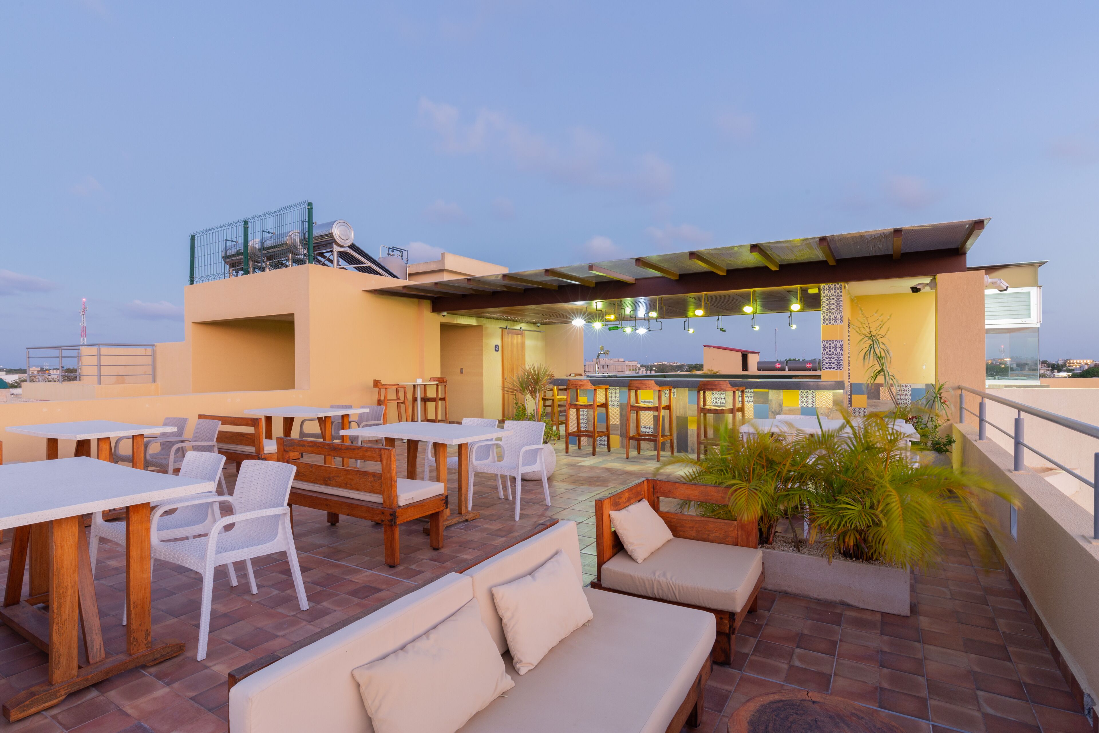 An outdoor patio area with tables and chairs, a bar, and a seating area with cushions.