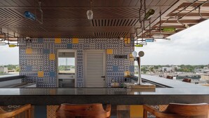 A modern bar area with a patterned backsplash, a large countertop, and wooden bar stools. - Biwa Tulum (Tulum)