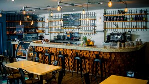 A restaurant with a bar area, wooden chairs, tables, and hanging light fixtures. - Biwa Tulum (Tulum)