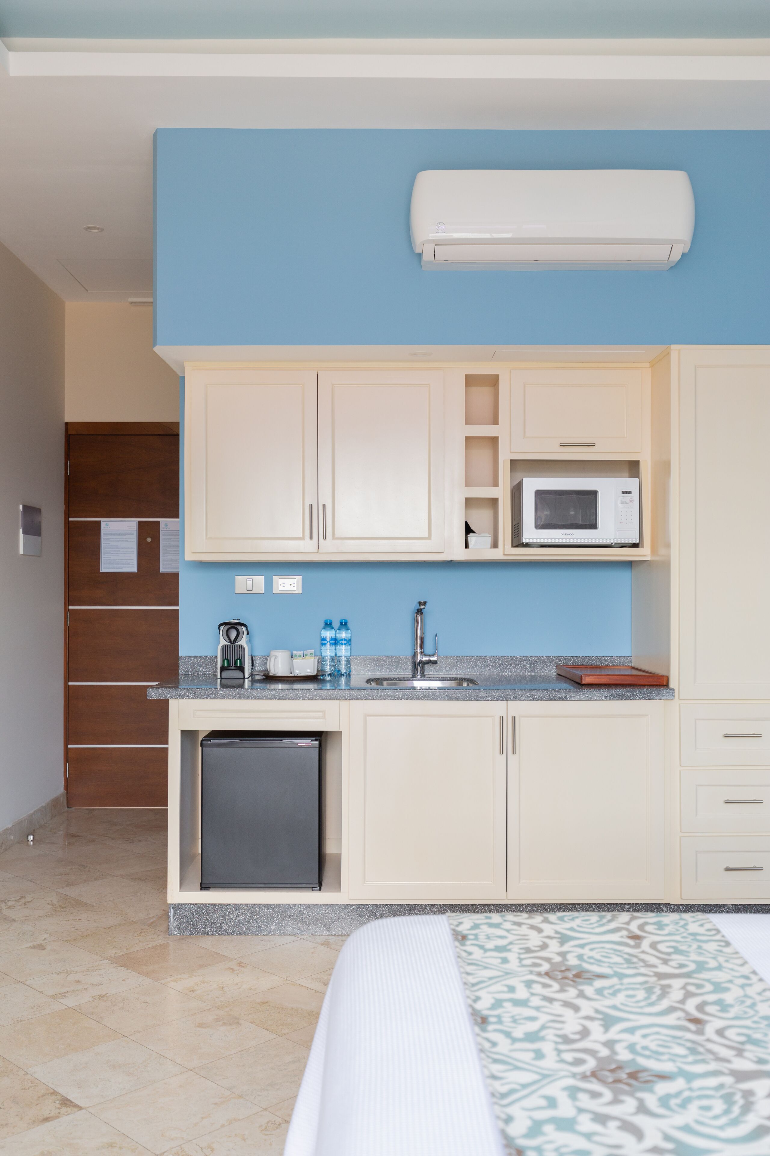 Habitación de hotel compacta con kitchenette, que incluye microondas, pileta y refrigerador.