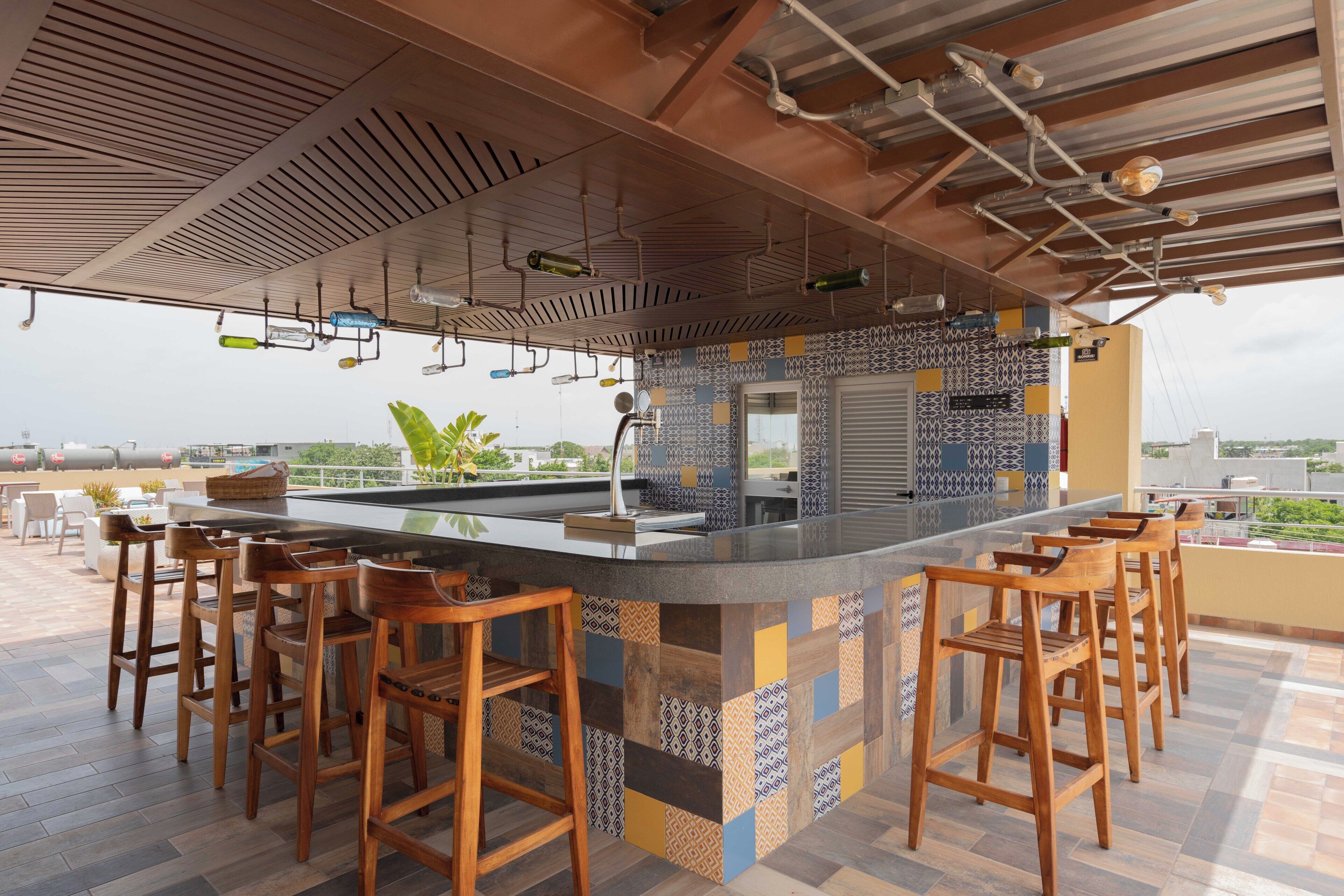 A bar area with a patterned tile backsplash, wooden bar stools, and a view of the cityscape.