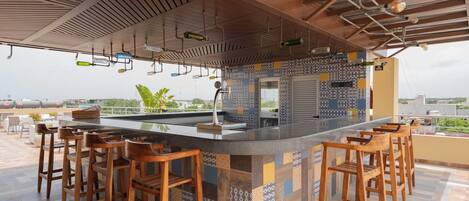 A bar area with a patterned tile backsplash, wooden bar stools, and a view of the cityscape.