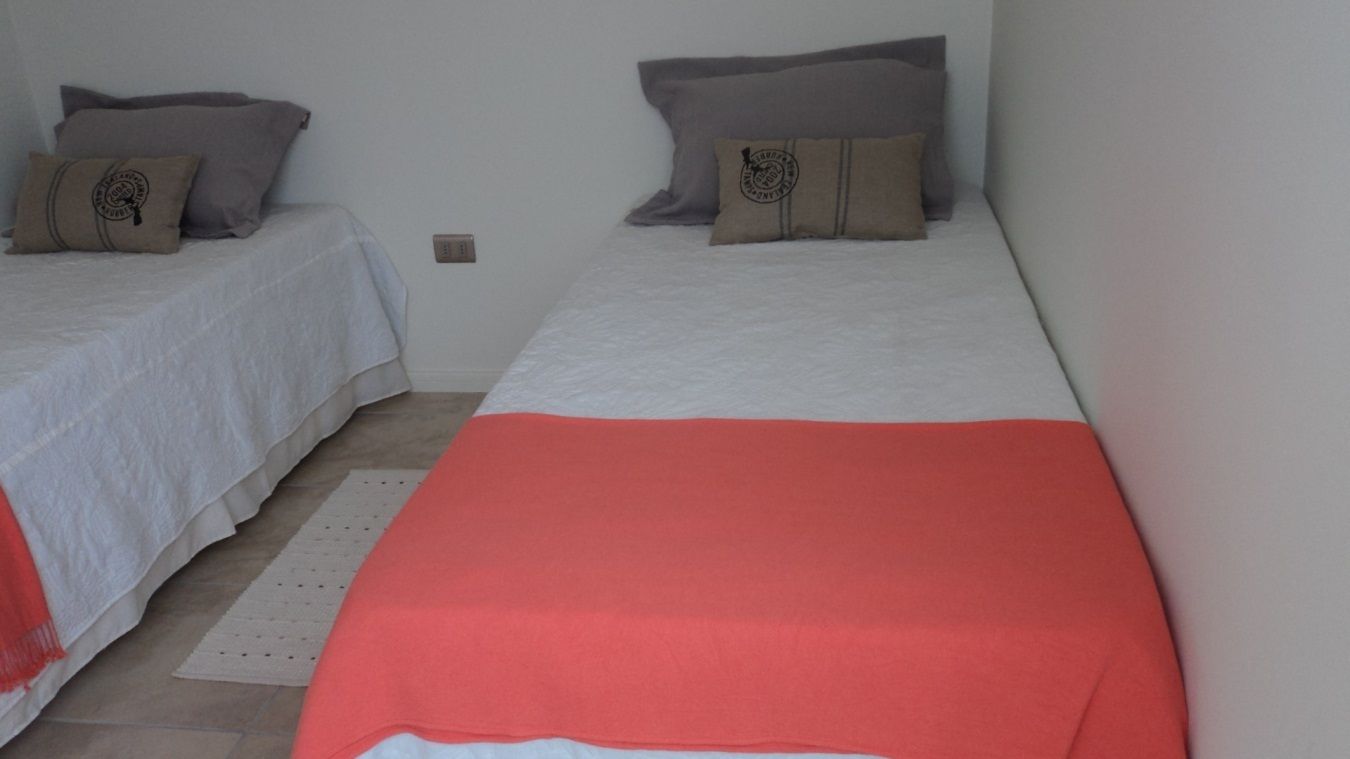Ein Schlafzimmer mit zwei Betten, jeweils mit Kissen und Decke.