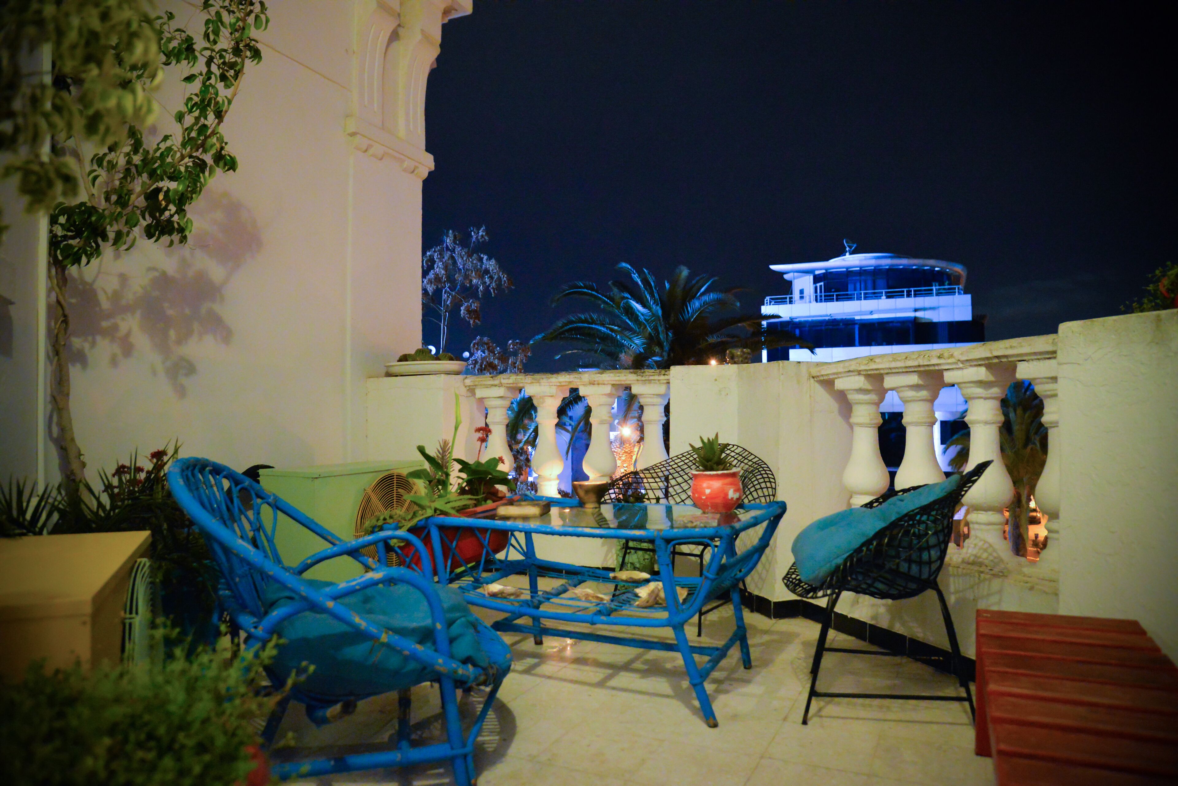 Une terrasse avec des chaises bleues, une table et des plantes en pot.