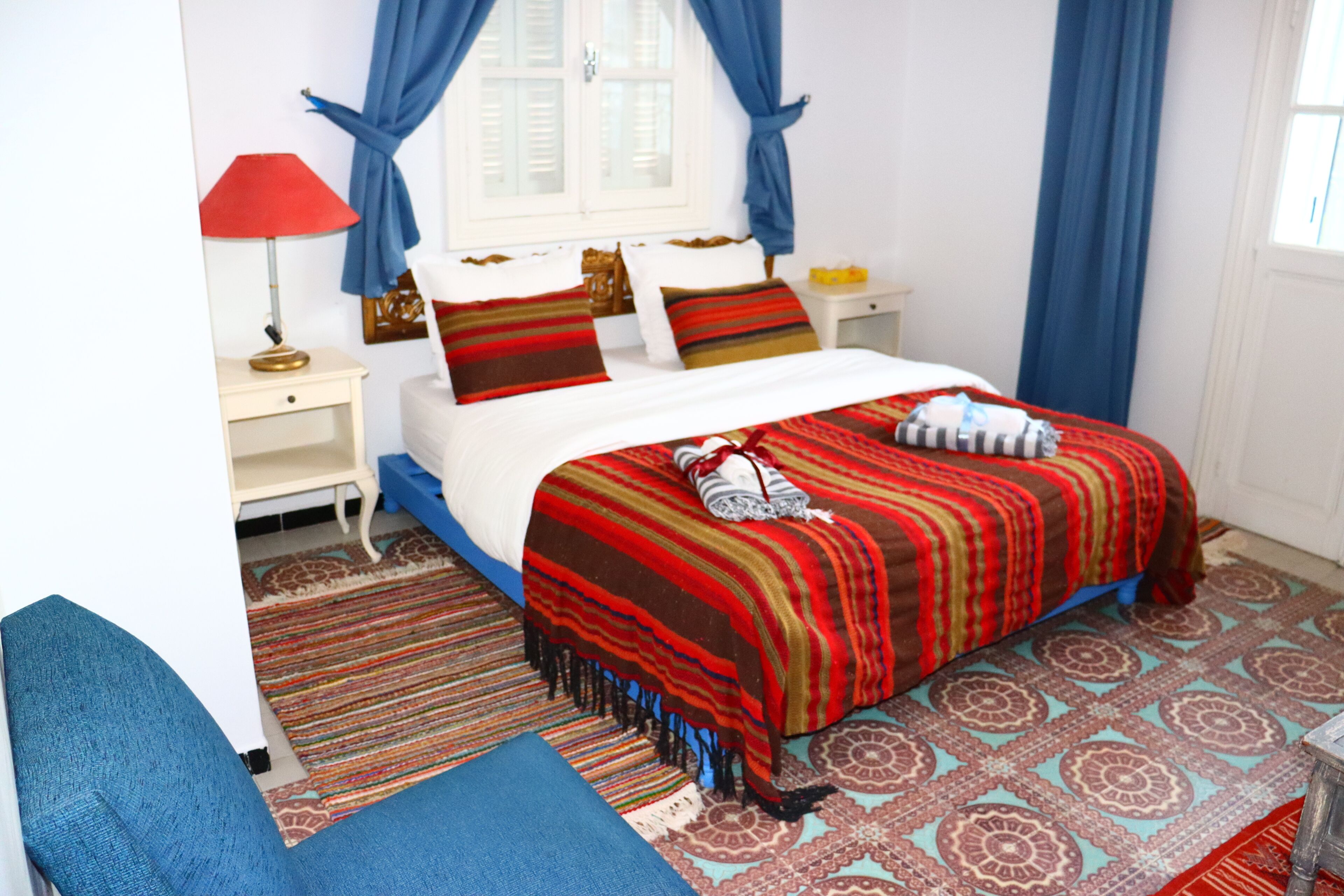 Ein Schlafzimmer mit einem Bett, einem Nachttisch, einer Lampe und einem Sessel.