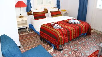 A bedroom with a bed, a nightstand, a lamp, and a chair.