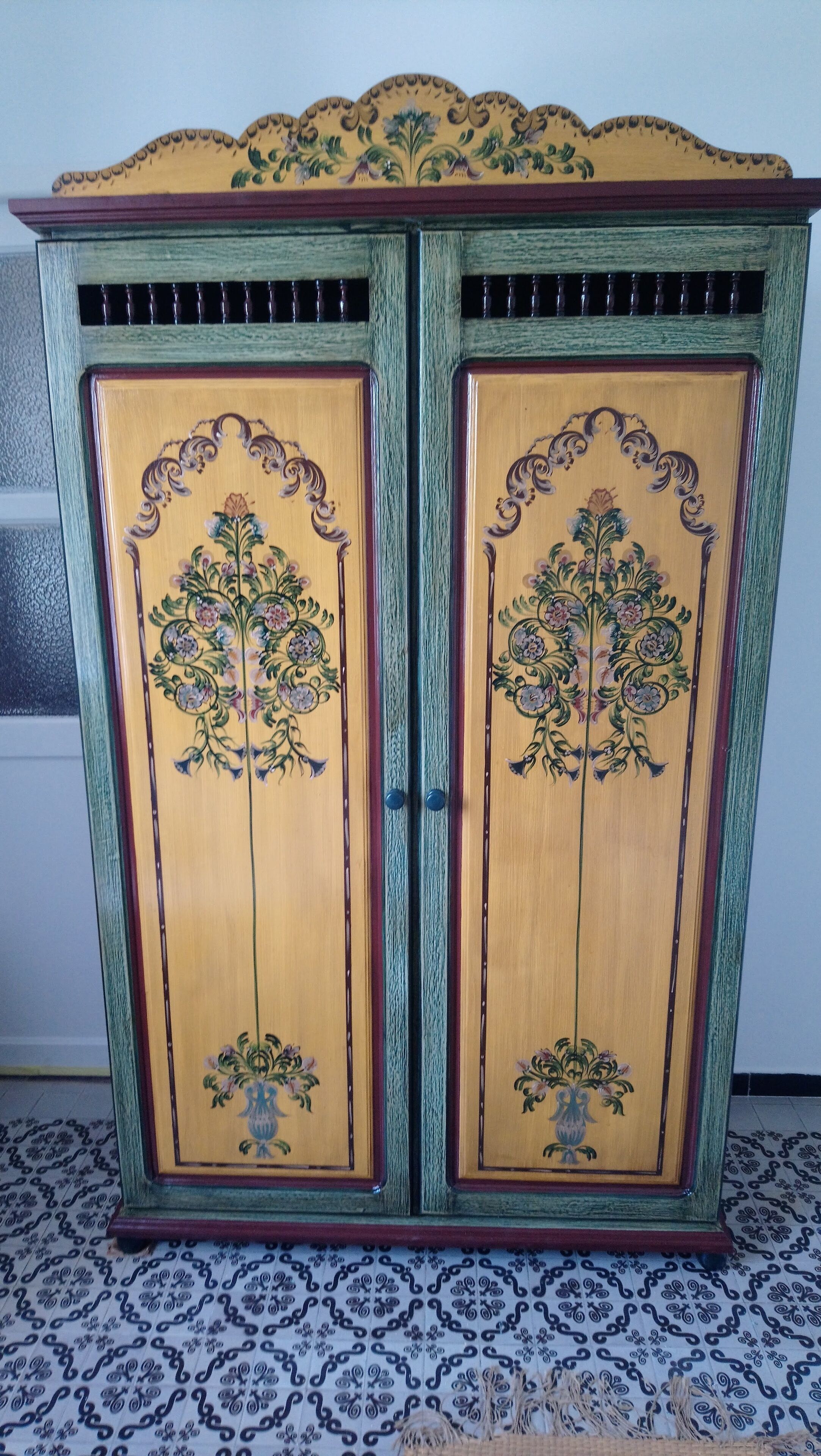 Un mueble de madera con detalles florales y un ribete verde.