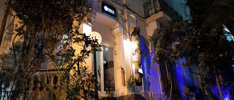 A building with a prominent entrance, a sign above the door, and a staircase leading up to the entrance.