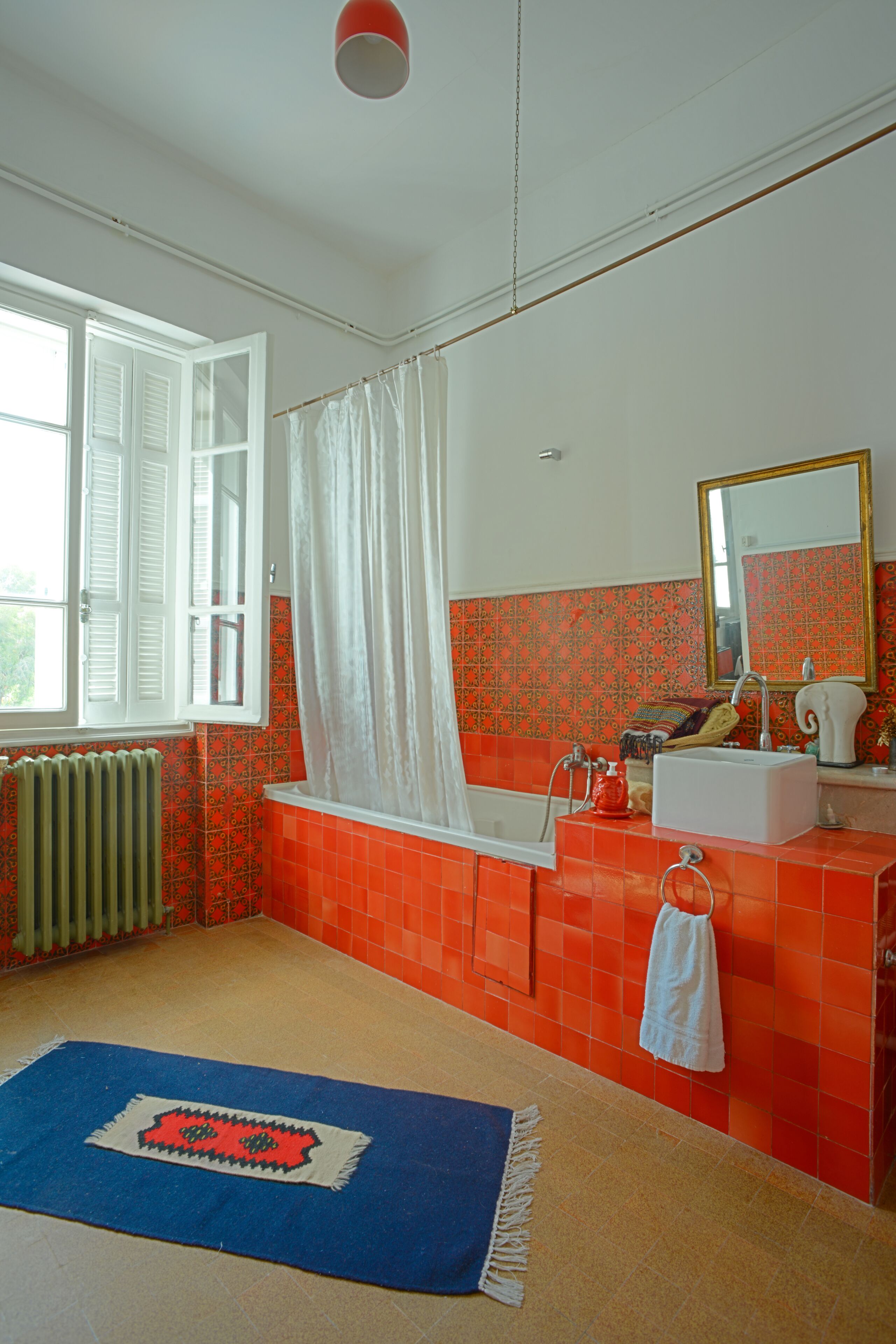 A bathroom with a bathtub, a sink, a mirror, and a window with white shutters.