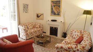 Sala de estar con sofás de estampado floral, una mesa de centro de vidrio, chimenea y cuadros en la pared.