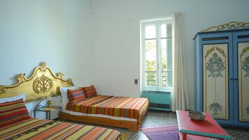A room with two beds, a table, and a cabinet.