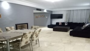 A living room with a dining table, chairs, a sofa, and a flat-screen TV. - Casa Stay (Casablanca)