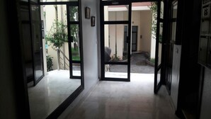 A hallway with glass doors leading to an outdoor area with a staircase and greenery. - Casa Stay (Casablanca)
