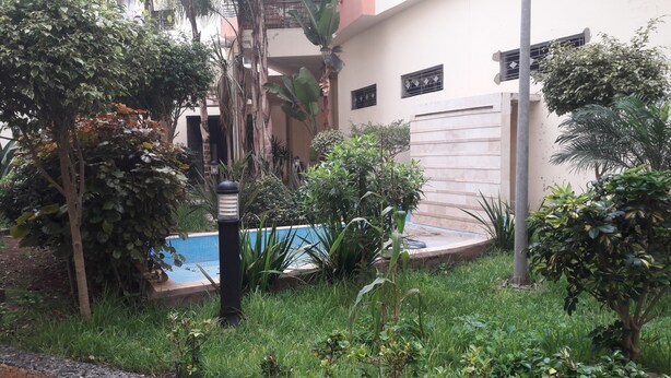 A residential area with a swimming pool surrounded by lush greenery, including various trees and shrubs. - Casa Stay (Casablanca)