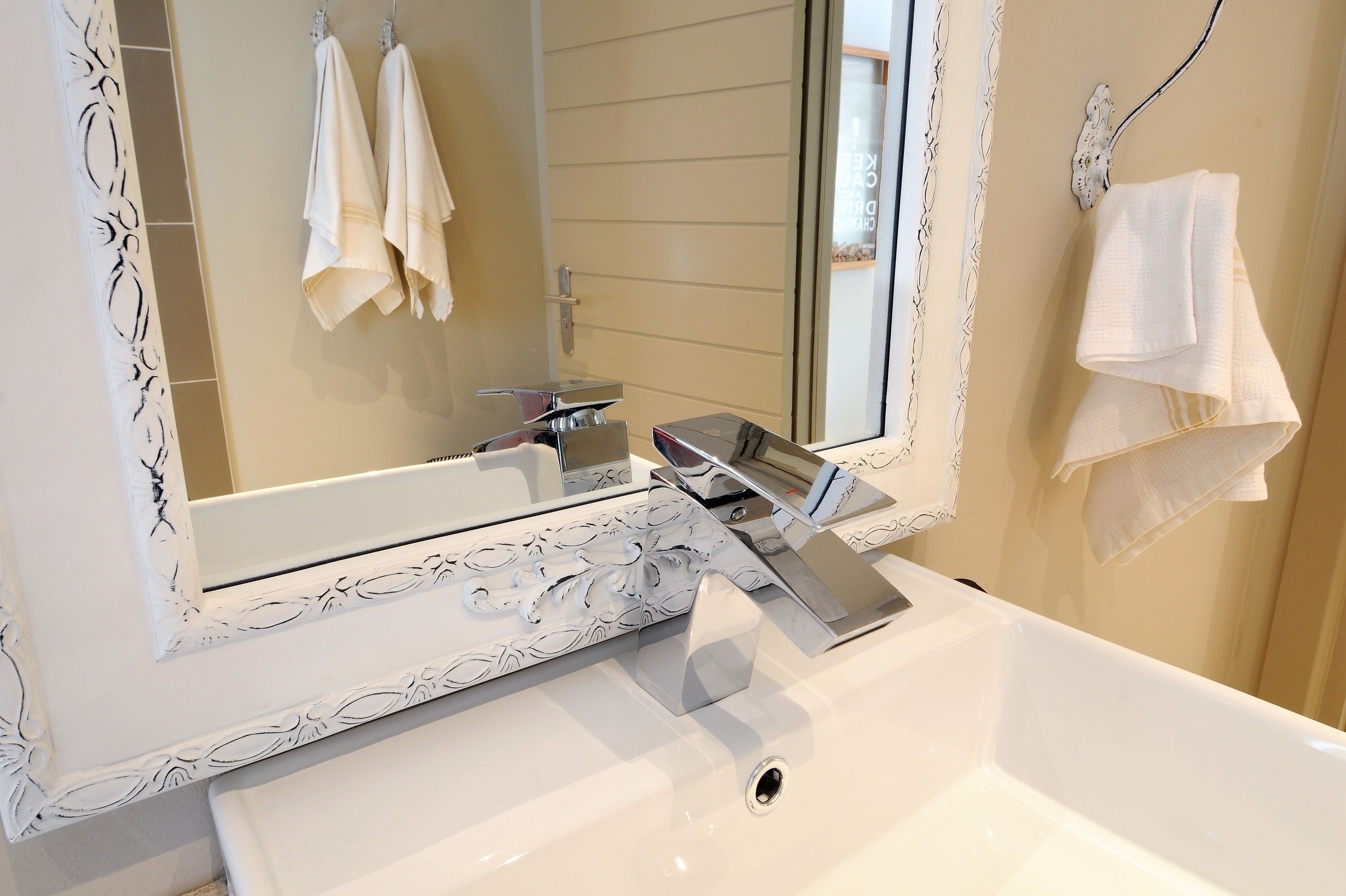 A bathroom with a white sink, a large mirror, and a towel rack.