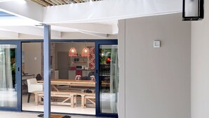 A modern interior with a bamboo ceiling, a dining area with a wooden table and chairs, and a kitchen in the background. - Ocean Breeze (Kenton on Sea)