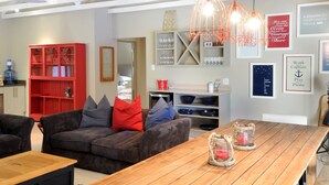 A modern living room with a wooden table, red and grey sofas, and a red cabinet. - Ocean Breeze (Kenton on Sea)