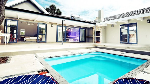 A modern house with a swimming pool, large windows, and a patio area. - Ocean Breeze (Kenton on Sea)