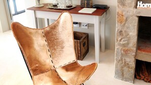 A modern living room with a leather chair, a painting of a landscape, a fireplace, and a table with decorative items. - Ocean Breeze (Kenton on Sea)