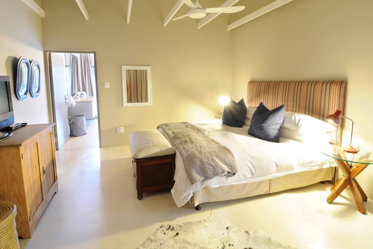A bedroom with a bed, bedside table, and a mirror.