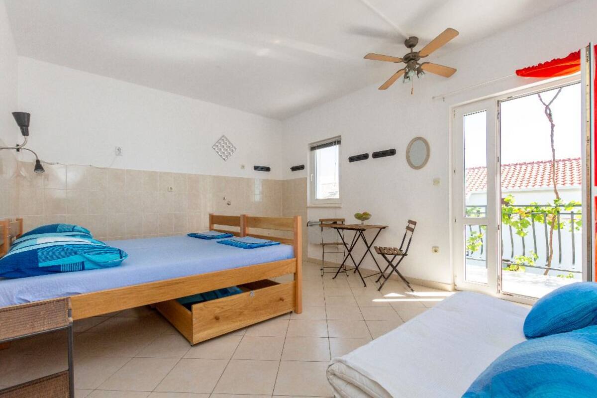 A bedroom with a bed, a desk, a chair, and a balcony with a view.