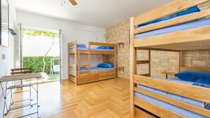 Una habitación con tres literas, una mesa de madera y un ventilador de techo.