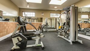 A gym with cardio machines, weight training equipment, and mirrors.