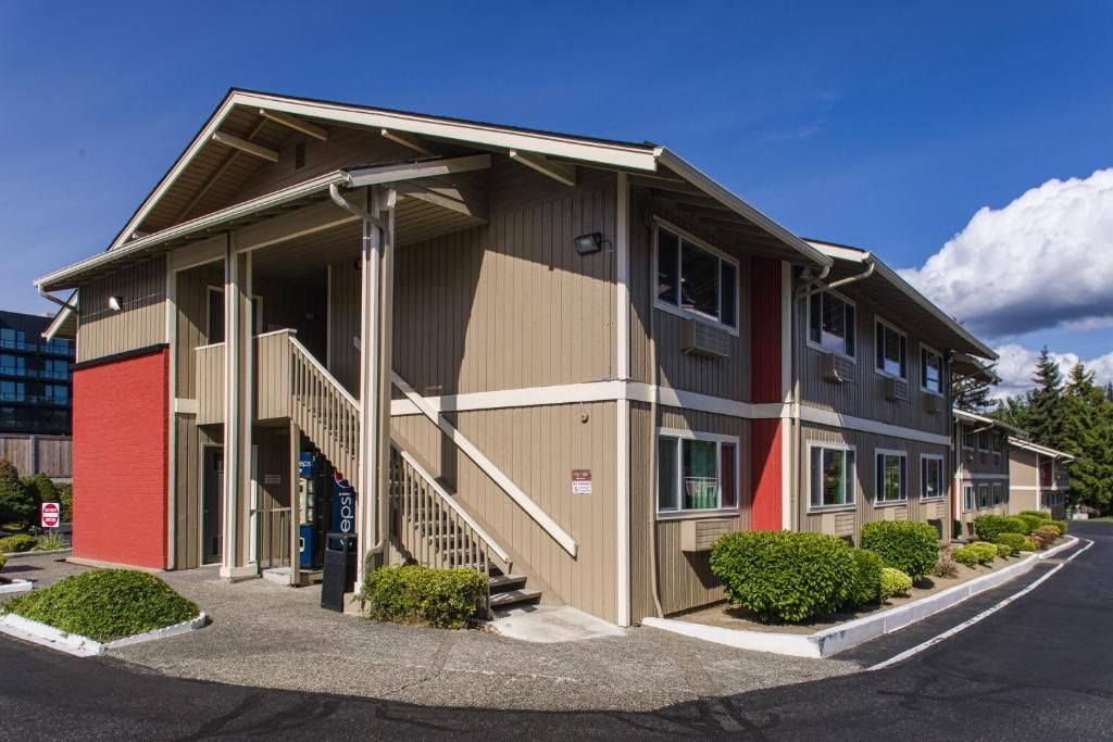 A multi-story building with a covered entrance, a staircase, and a parking lot.