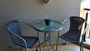 A small outdoor seating area with two wicker chairs and a glass table, featuring a heart-shaped decoration on the wall. - 12 Simonsplein (Stellenbosch)