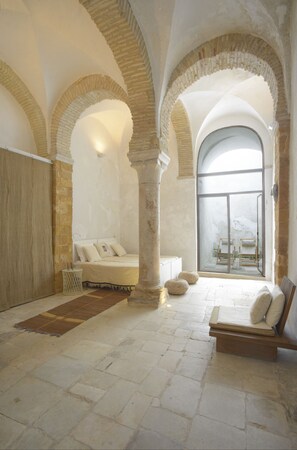 A spacious room with a large bed, a seating area, and a view through a glass door. - La Chambre Bleue (Tunis)