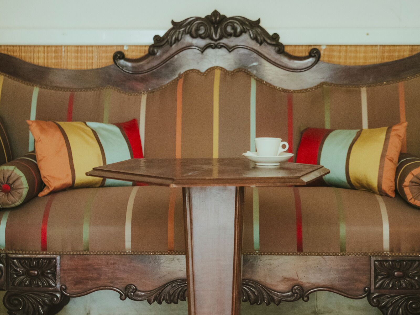 A vintage sofa with a cup and saucer on a wooden table in front.