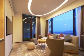 Une chambre d’hôtel moderne dotée d’une grande fenêtre, d’un canapé, d’une table basse et d’un téléviseur.