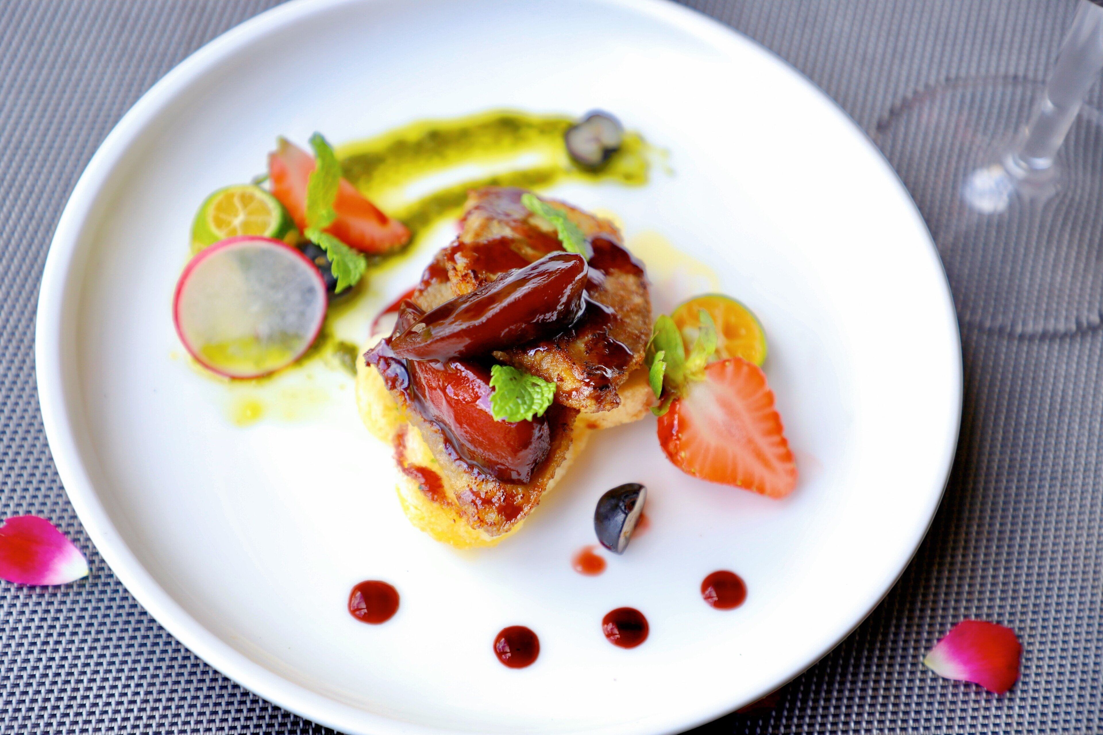 Un plato blanco con un guiso, decorado con hierbas y salsa.