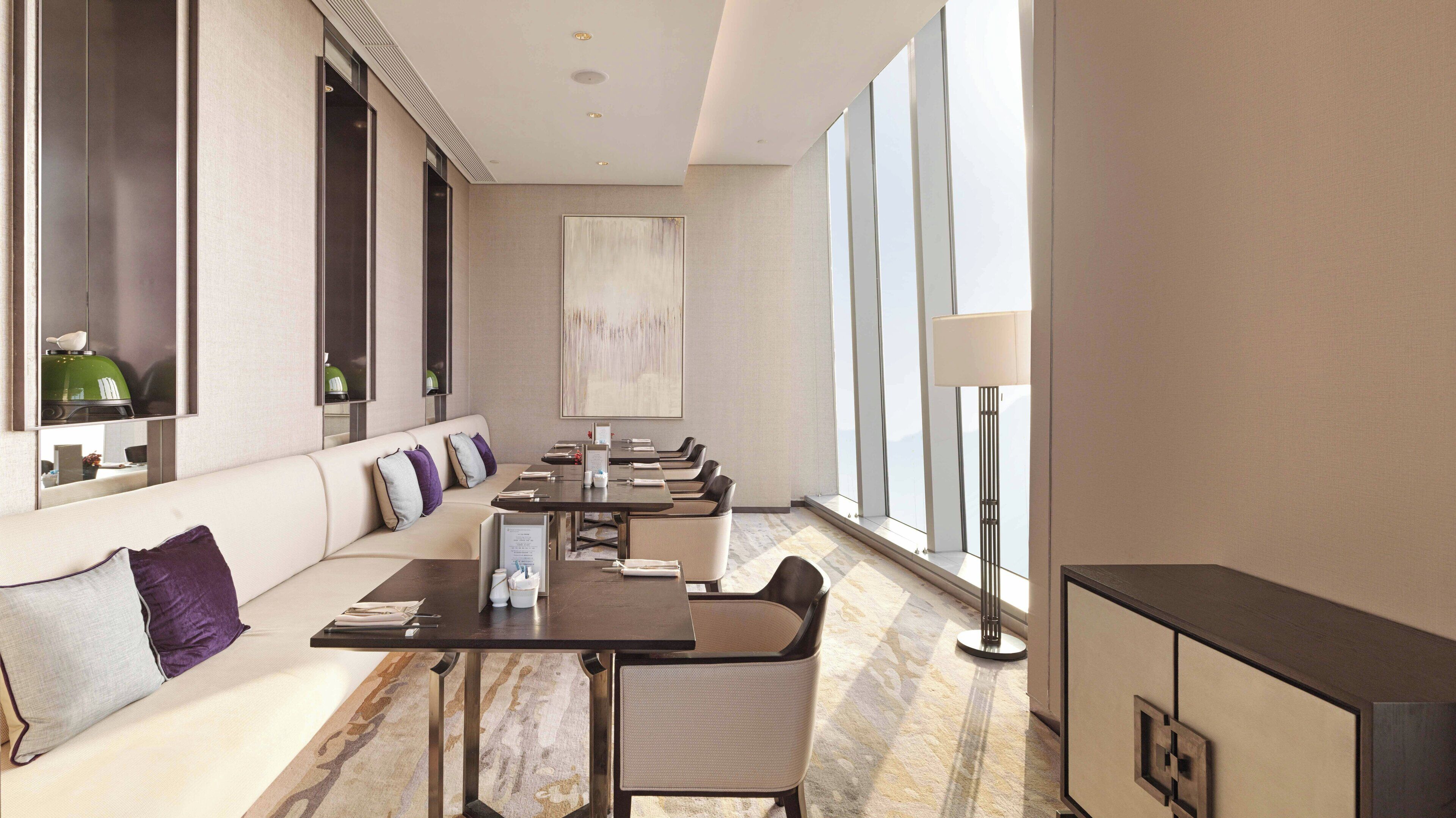 A modern conference room with a long table, comfortable seating, and large windows.