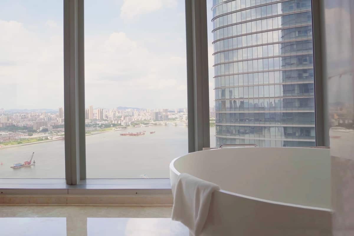 A room with a large window, a white table, and a view of a cityscape and river.