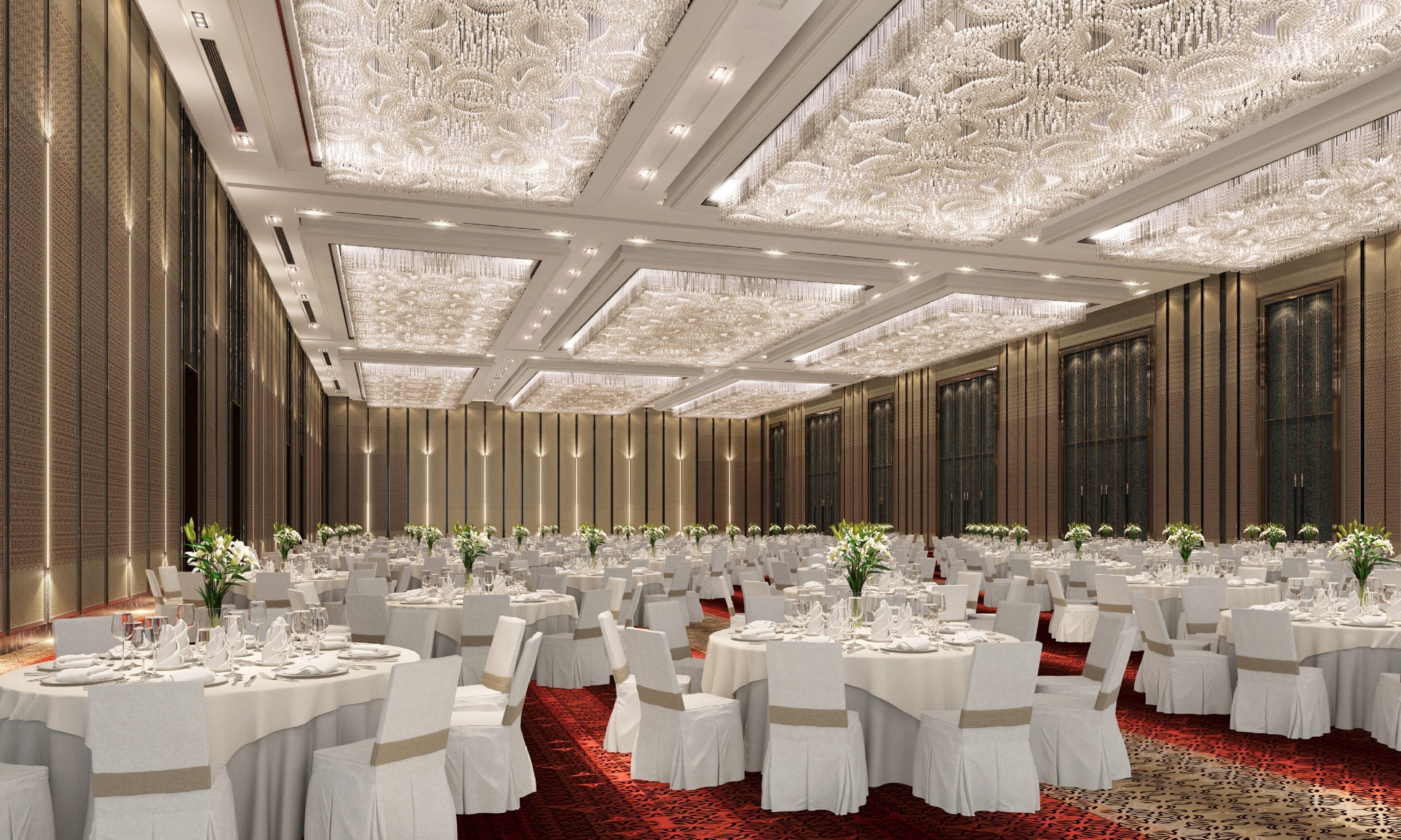 A banquet hall with round tables, white chairs, and a red carpet.