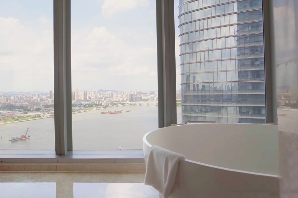 A room with a large window, a white table, and a view of a cityscape and river.