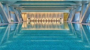 A large indoor swimming pool with a modern design, featuring a central seating area with sun loungers and a patterned ceiling. - InterContinental Guangzhou Exhibition Center by IHG (Guangzhou)