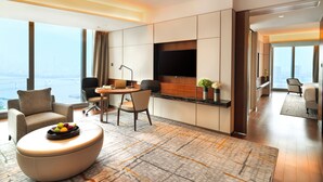 Habitación de hotel moderna con un gran ventanal, televisión de pantalla plana, zona de comedor y sala de estar con frutero.