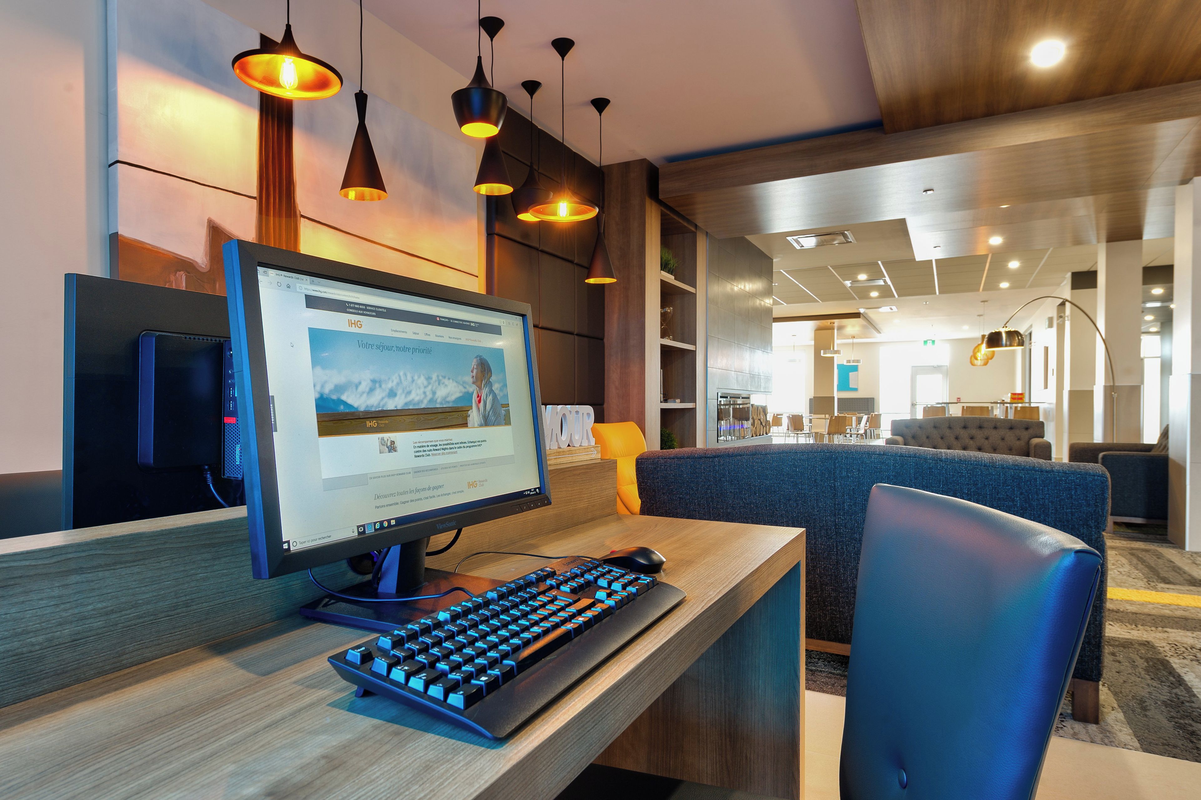 Un espacio de oficina moderno con una computadora de escritorio, un teclado y una silla de oficina azul.