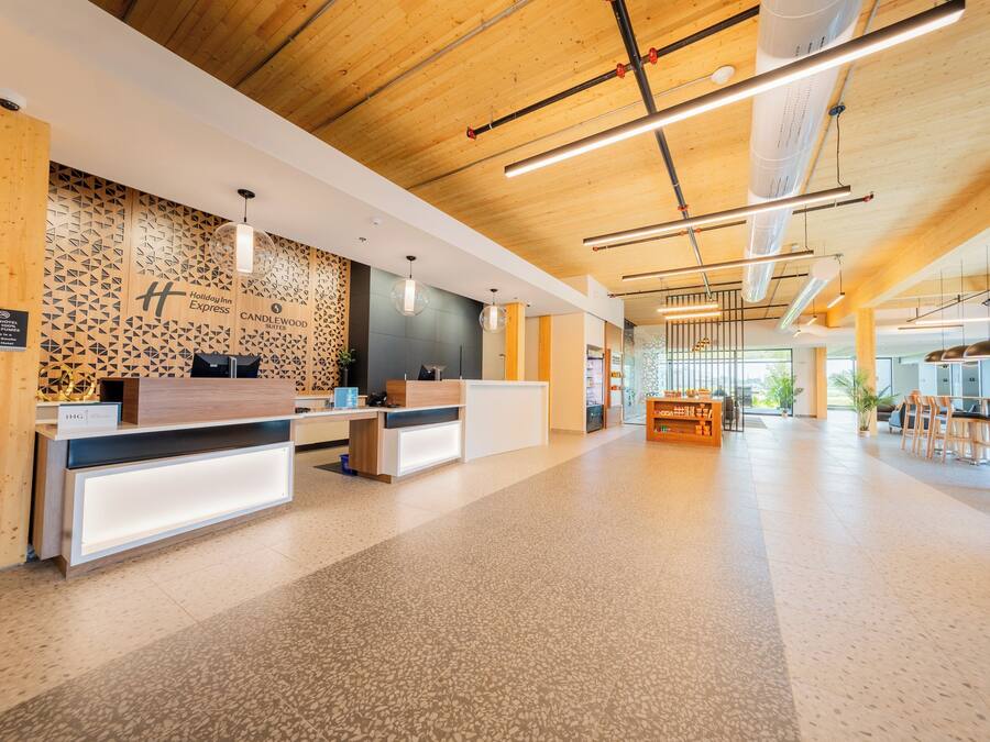 Un área de recepción de hotel moderna con techo de madera, pared con diseño y mostrador de recepción.