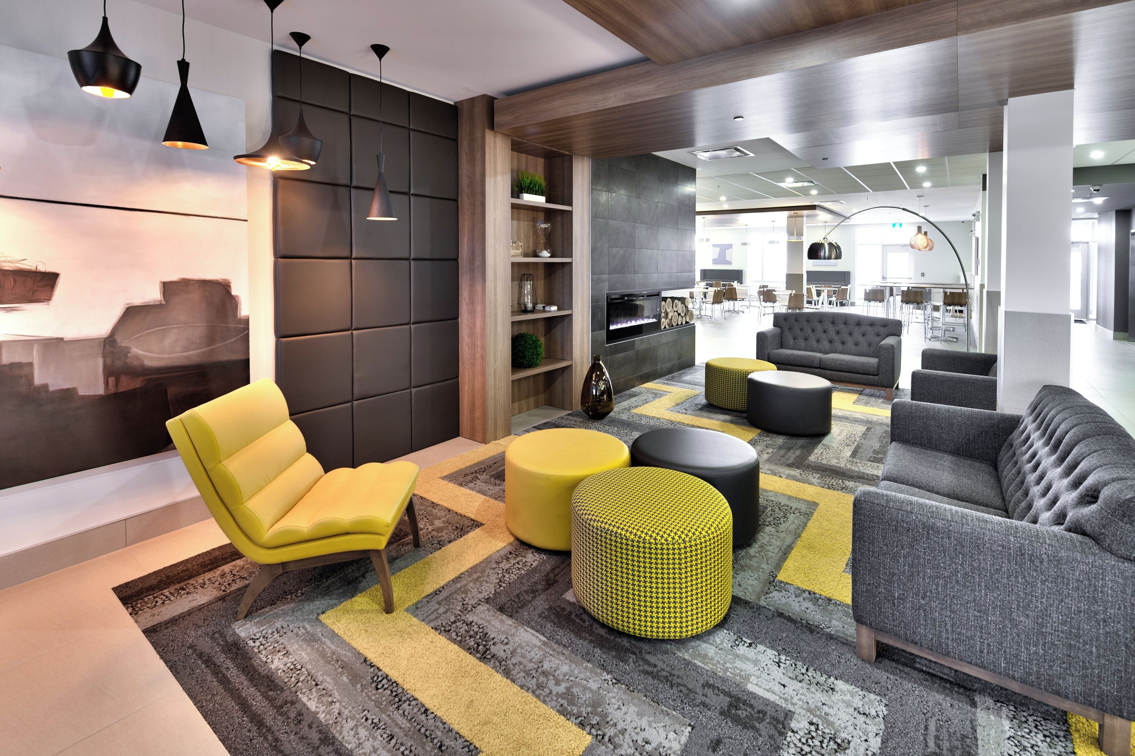 Un interior moderno con sofá, un reposapiés amarillo y una zona de estar con una silla amarilla.
