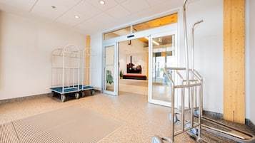 A spacious lobby with a clear view of the entrance, a metal cart, and a blue bench.