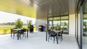 Un patio al aire libre con una mesa, sillas, una parrilla y vistas del paisaje circundante.