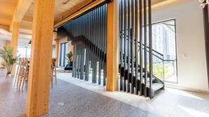 Ein modernes Interieur mit Holzbalken, einer Treppe und Blick ins Freie.