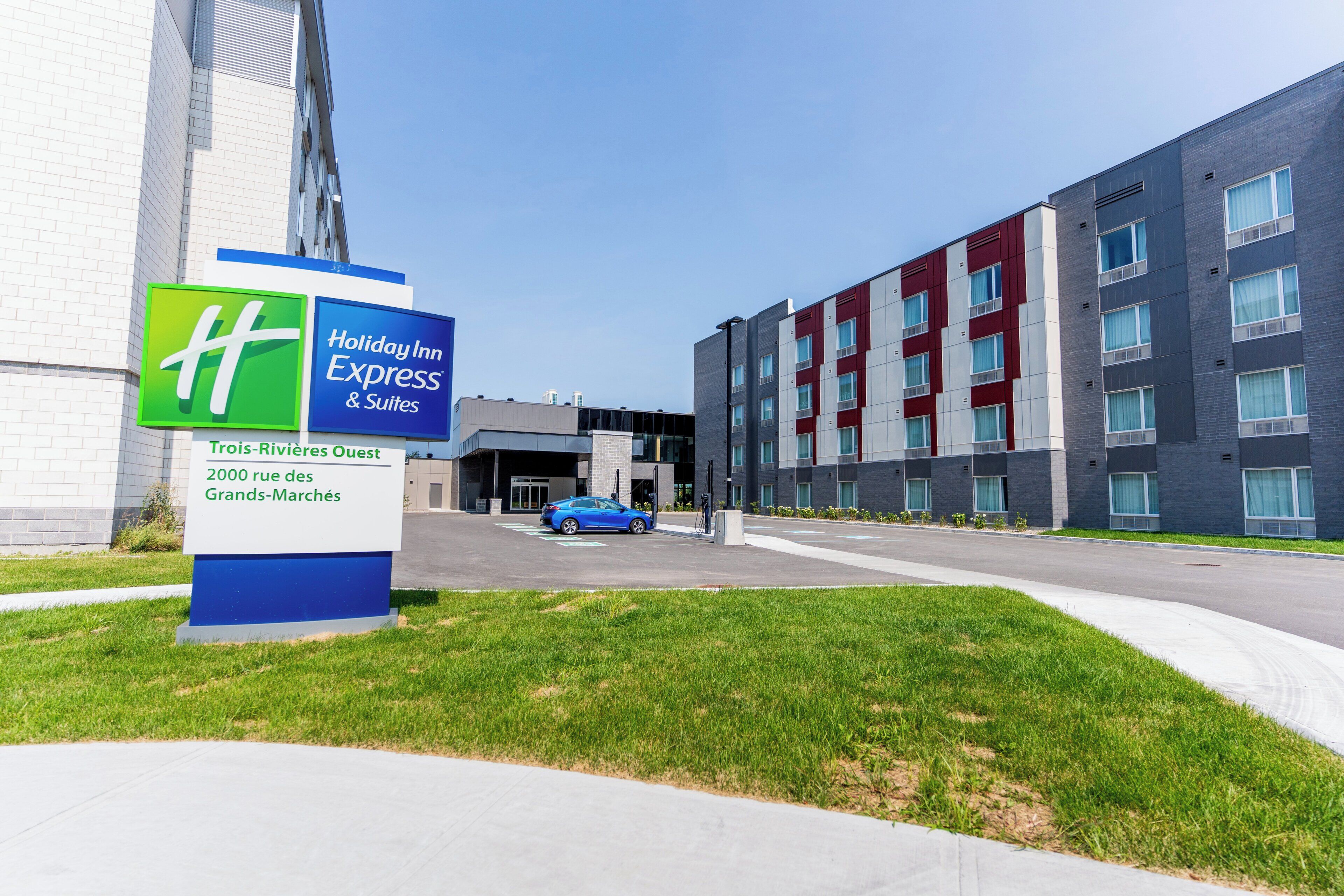 A Holiday Inn Express & Suites sign with a modern building in the background.