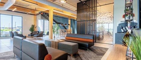 A modern lounge area with sofas, a staircase, and a reception desk.