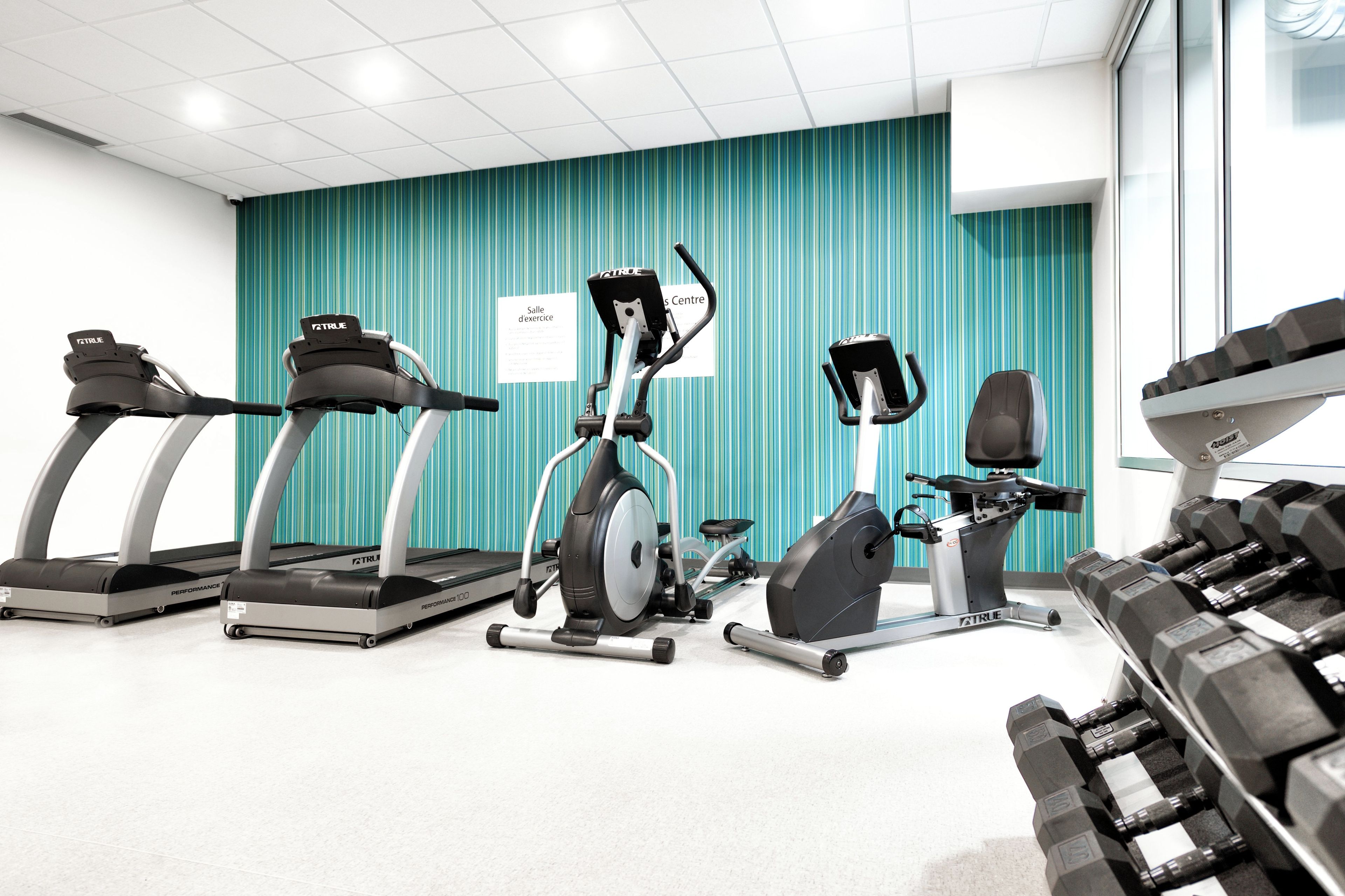 Un gimnasio con cintas de correr, elíptica y mancuernas.